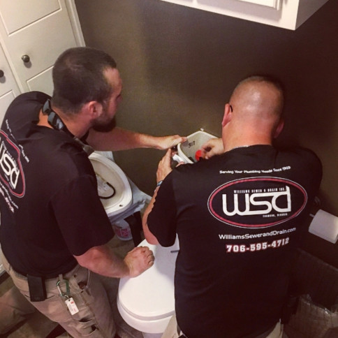 Williams Sewer & Drain technicians repairing a toilet on the job